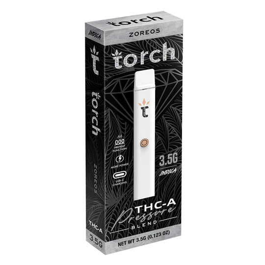 A Torch-branded THC-A blend vape pen labeled "Torch THCA Pressure Blend Disposable | 3.5g," featuring 3.5g Indica extract, is encased in predominantly black packaging adorned with intricate designs and comprehensive details about the product's functions and contents.