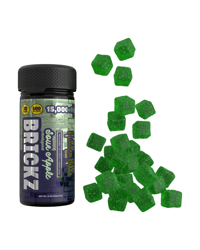 A black container labeled "Hidden Hills Heady Blend Brickz Gummies | 15000mg" with green sour apple gummies scattered beside it. The container notes 15,000 MG and 500 MG per serving, featuring Delta 9 live resin for an enhanced experience.